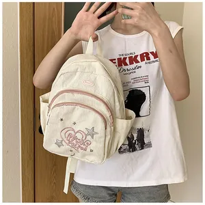 Détail d'un mini sac à dos en velours côtelé crème avec broderie coeur rose et poche