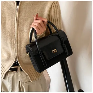 Close-up of black crossbody bag with gold COIH '2DN logo and polished metal buckle