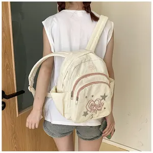 Détail d'un sac à dos en velours côtelé crème avec broderie cœur Power Puff et étoiles
