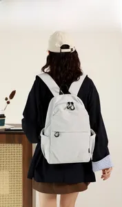 Detail of light grey waterproof nylon mini backpack featuring a front pocket and side pockets
