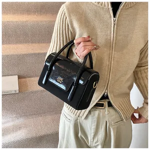 Close-up of black retro square handbag with metallic logo and textured patchwork detail