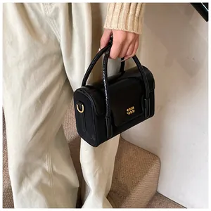 Close-up of black crossbody bag with gold hardware and logo on leather and fabric texture