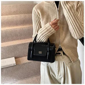 Detail of black glossy patent leather handbag with gold metal logo on stairs background