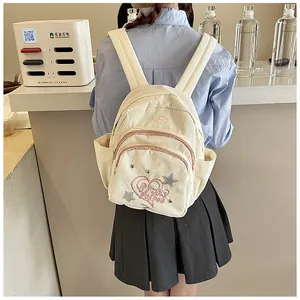 Détail du sac à dos en velours côtelé crème avec broderie cœur rose et patchs d'étoiles