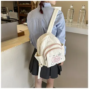 Gros plan d'un sac à dos en velours crème avec broderie coeur et zip rose de détail