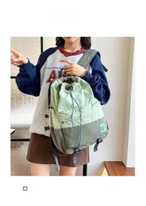 Detail of mint and olive green nylon backpack with drawstring closure and square logo