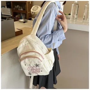 Vue détaillée du mini sac à dos en velours côtelé crème avec broderie et poche latérale