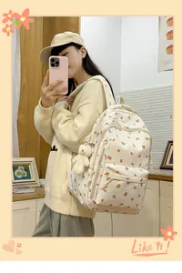 Detail of cream floral backpack with orange fruit patterns and a white plush bear charm