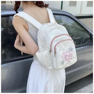 Détail d'un mini sac à dos en velours côtelé blanc avec broderie cœur et patchs étoiles