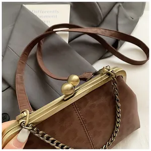 Détail du sac coquille en daim marron avec cadre en laiton et fermoir à perles sécurisé