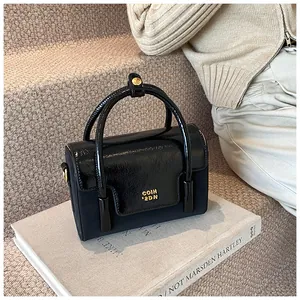 Detailed close-up of a black textured square handbag with golden metallic logo on art book