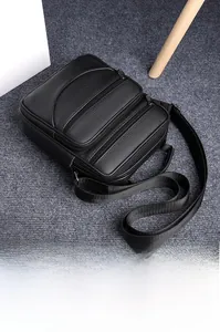 Detailansicht der schwarzen Lederstruktur und funktionalen Reißverschlüsse der Herrentasche