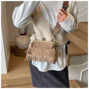 Detail van vintage suède tas met franjes en geweven schouderband in bohemien stijl