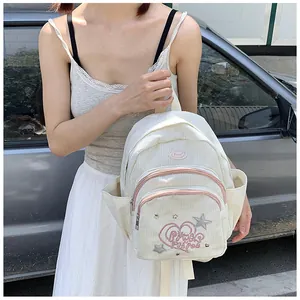 Détail de la texture du sac à dos en velours côtelé blanc avec fermeture rose et broderie