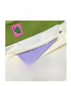 Detail of multi-color drawstring backpack showing front pocket and pink leaf logo patch