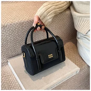 Detail of black leather handbag with gold metal logo and textured paneling
