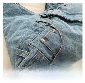 Detail of light blue denim tote with yellow stitching, metal rivets and top zipper