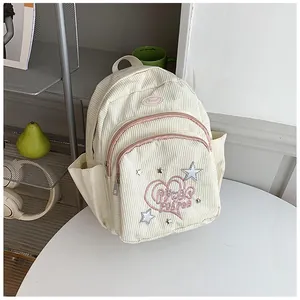 Détail de la texture en velours côtelé beige et broderie Power Puff sur le sac à dos