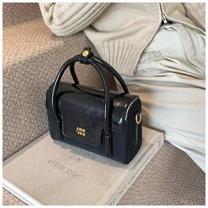 Detail of elegant black textured handbag with golden hardware logo on book surface