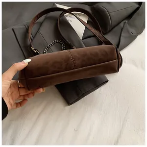 Détail d'un sac bandoulière marron en daim avec coutures de base et chaîne en métal