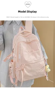 Dettaglio dello zaino rosa con ricamo e ciondolo a forma di luna di peluche gialla