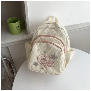 Détail du sac à dos en velours côtelé avec broderie cœur rose et rivets étoiles