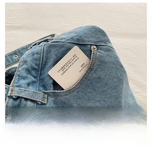 Detailed view of light blue denim bag featuring front pocket with orange stitching and rivets