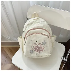 Détail d'un mini sac à dos en velours côtelé crème avec broderies de cœurs roses