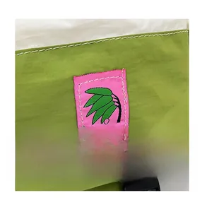 Detail of green nylon school backpack showing durable fabric texture and pink leaf patch