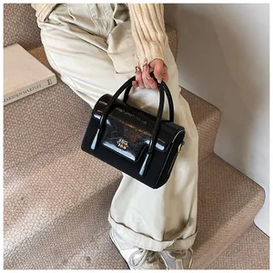 Detail of black crossbody bag with logo lettering on glossy flap and matte finish