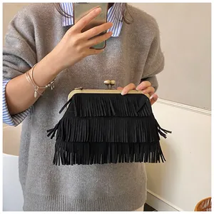 Detail van vintage zwarte suède clutch met drielaagse franjes en goudkleurige parelsluiting