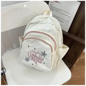 Détail du sac à dos en velours côtelé crème avec broderie cœur rose et poches