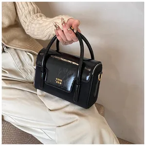 Close-up of black handbag showing contrast between patent leather and matte fabric