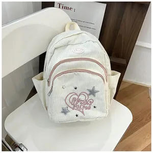Détail d'un sac à dos mignon en velours côtelé avec broderie cœur et texture sur chaise