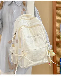 Dettaglio dello zaino in nylon crema con ricamo e ciondolo a forma di stella di peluche