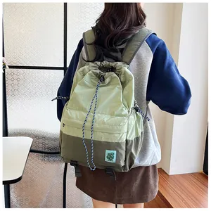 Detail of green nylon drawstring backpack with floral patch and braided cords
