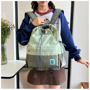 Detail of green nylon drawstring backpack with two-tone splicing and zipper pocket