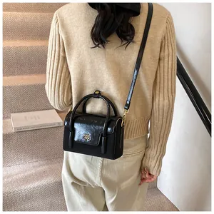 Detailed back view of a black mini crossbody bag styled with beige knitwear