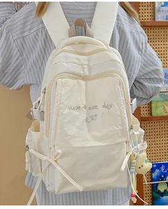 Dettaglio dello zaino scolastico in nylon crema con fiocco e ciondolo a forma di stella