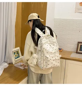 Detail of white floral backpack with adjustable side buckle and cute plush bear charm