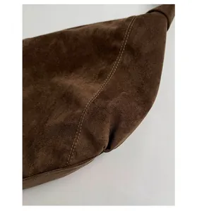 Detail view of premium dark brown suede fabric with neat reinforced stitching on a large bag