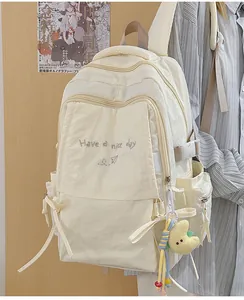Dettaglio zaino scolastico crema con ricamo e ciondolo a forma di luna in peluche