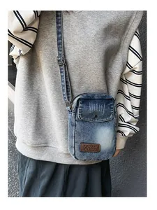 Detail of blue denim crossbody bag with adjustable strap and front pocket on a model