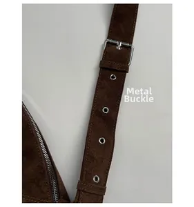 Detail of adjustable suede strap with silver metal grommets and hardware on brown bag