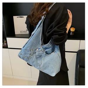 Detail of light blue washed denim tote bag with metal button and pocket reconstruction