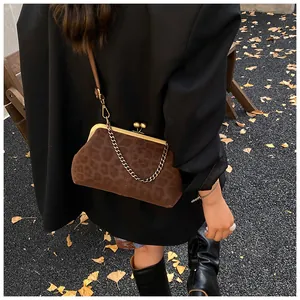 Détail du sac léopard avec fermoir bronze sur un fond de feuilles de ginkgo dorées