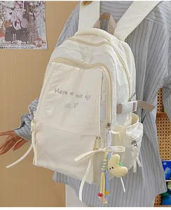 Dettaglio dello zaino in nylon beige con fiocchi laterali e ciondolo a forma di luna