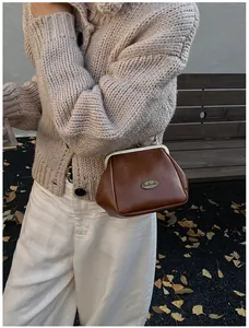 Détail du sac vintage en cuir marron avec étiquette métal handmade et bandoulière