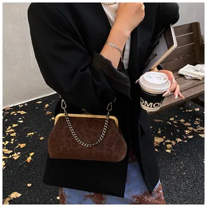Détail du sac de soirée léopard porté par un mannequin dans un décor extérieur d'automne