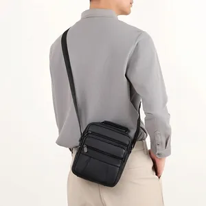 Minimalist black pebble leather shoulder bag with multiple zippers shown on male model